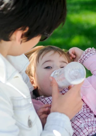 baby-girl-drinking-milk-from-baby-bottle-mother-feeding-daughter-from-bottle