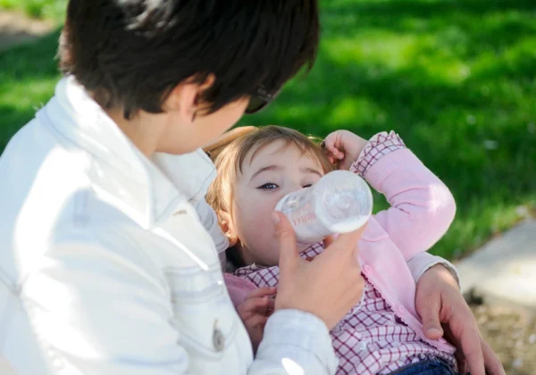 baby-girl-drinking-milk-from-baby-bottle-mother-feeding-daughter-from-bottle